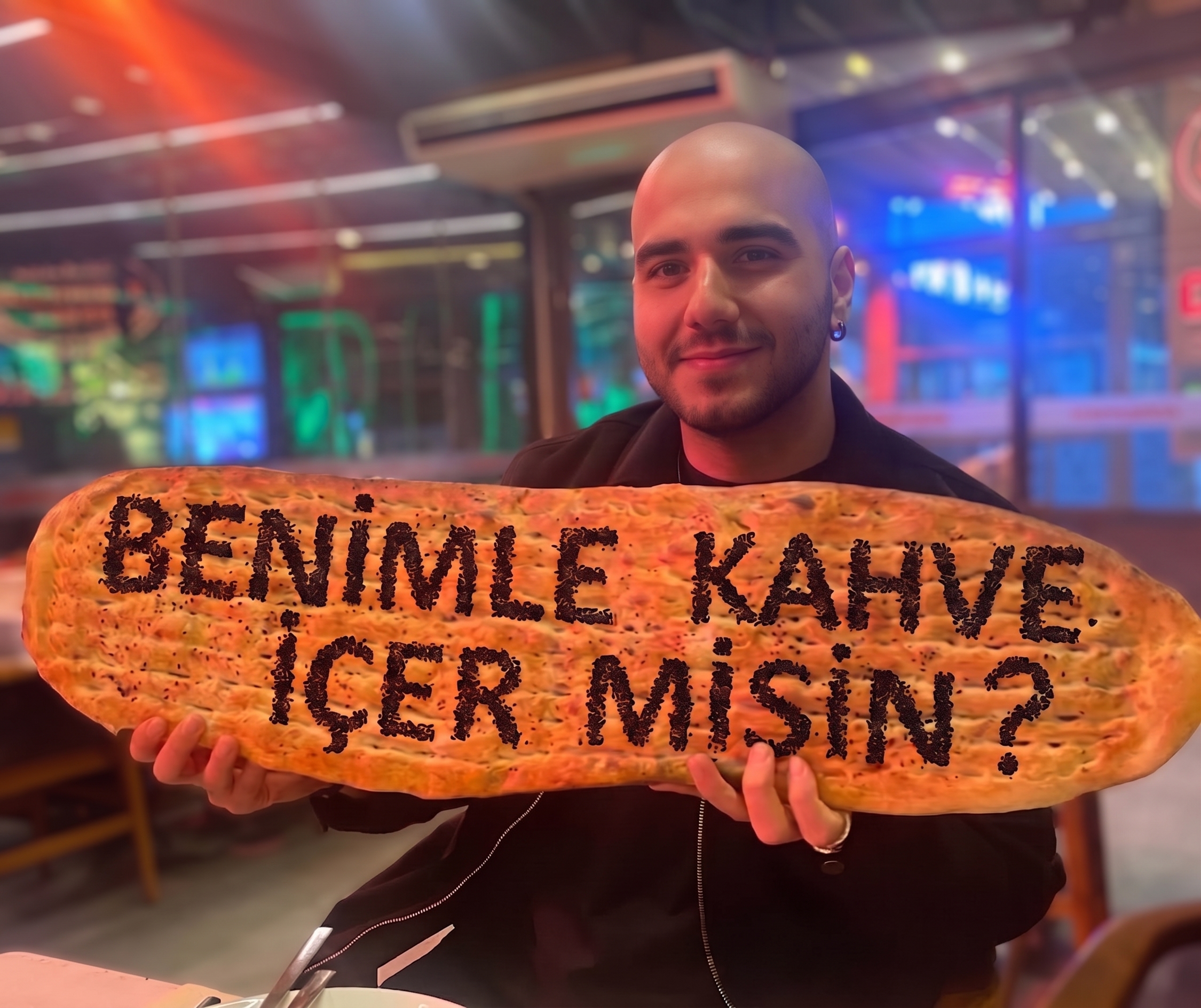 Eren dev bir ekmek tutuyor. Üzerinde Benimle kahve içer misin yazıyor.